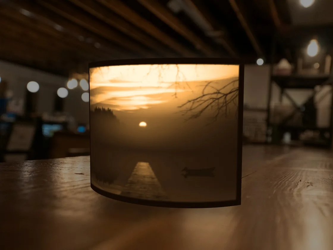 Curved lithophane of a sunset over a jetty, glowing on a café table